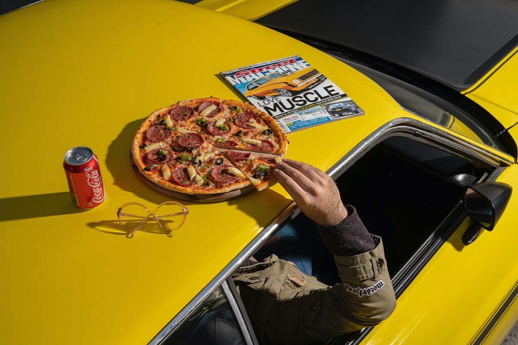 pizza and coke can on top of pizza snob's yellow car