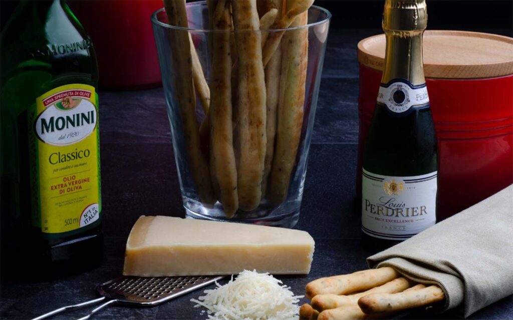 olive oil parmesan cheese and thin breadsticks on the table