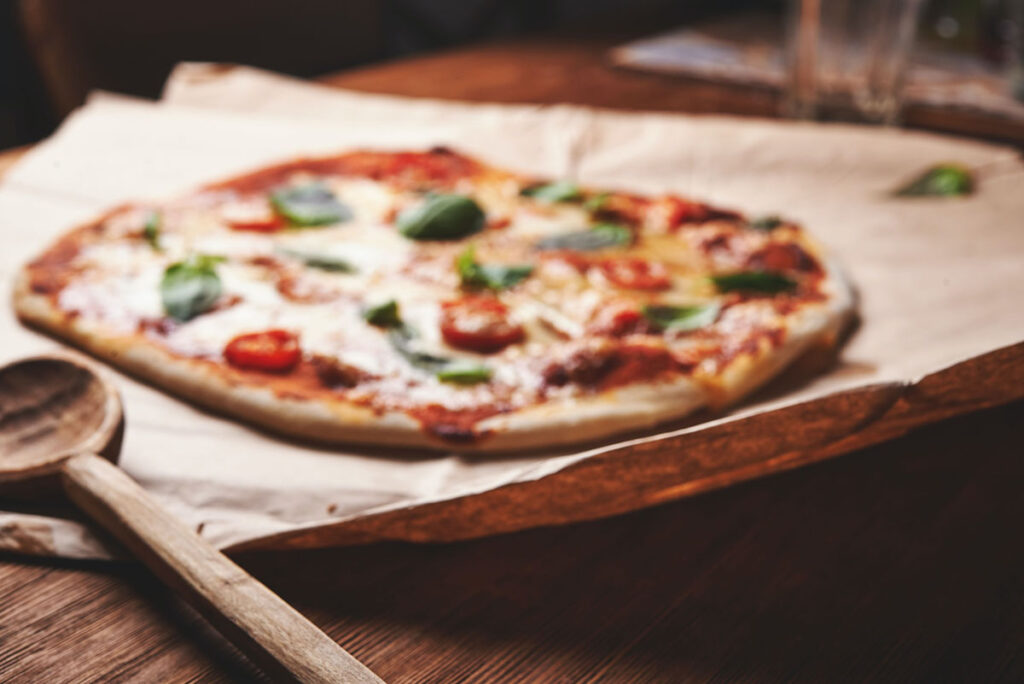 classic pizza on a table with cutting board and wooden spoon